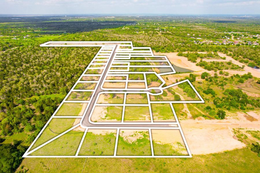 An aerial perspective showcases a planned community with delineated lots amidst lush natural surroundings and winding roads.
