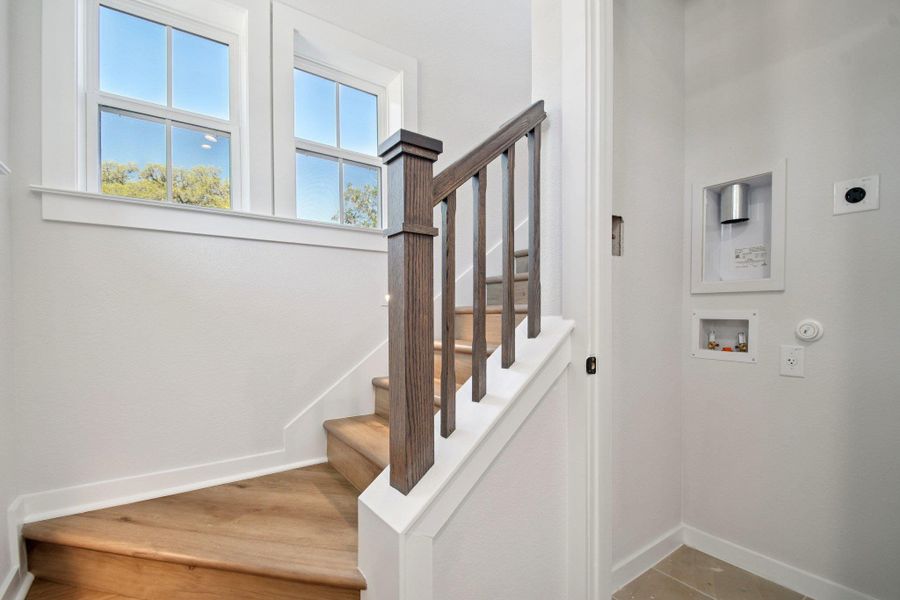 LVP stairs ascend to sun-filled windows, complementing the adjacent laundry utility hookups. LVP stairs ascend to sun-filled windows, complementing the adjacent laundry utility hookups.