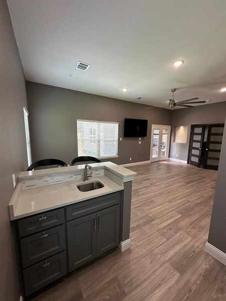 Kitchen with a peninsula, gray cabinetry, open floor plan, dark wood-style flooring, and recessed lighting