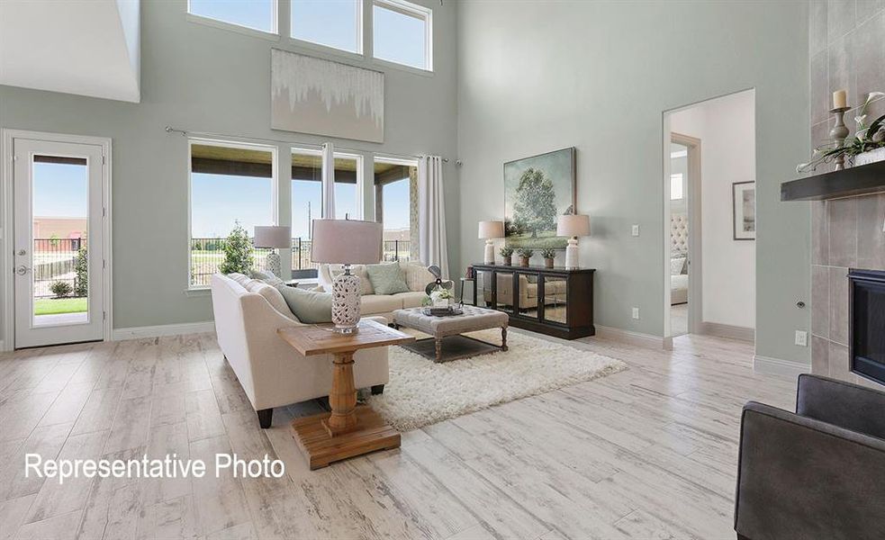 Living room with a healthy amount of sunlight, a tiled fireplace, and light hardwood / wood-style flooring