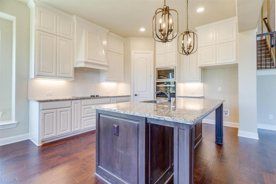 Kitchen with white cabinets, premium range hood, and dark wood-type flooring