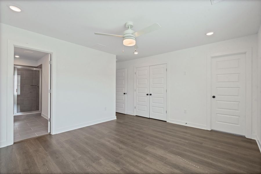 Wood-finish flooring, recessed lighting, ceiling fan, white interior doors, and a tile-floor bathroom with a glass shower enclosure