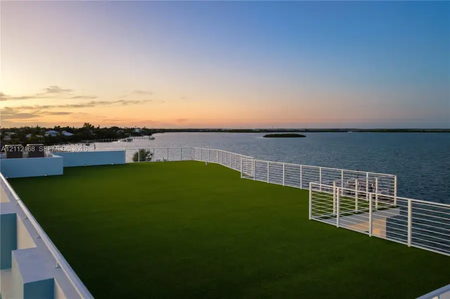 Expansive rooftop terrace featuring synthetic turf flooring and horizontal cable railing Expansive rooftop terrace featuring synthetic turf flooring and horizontal cable railing