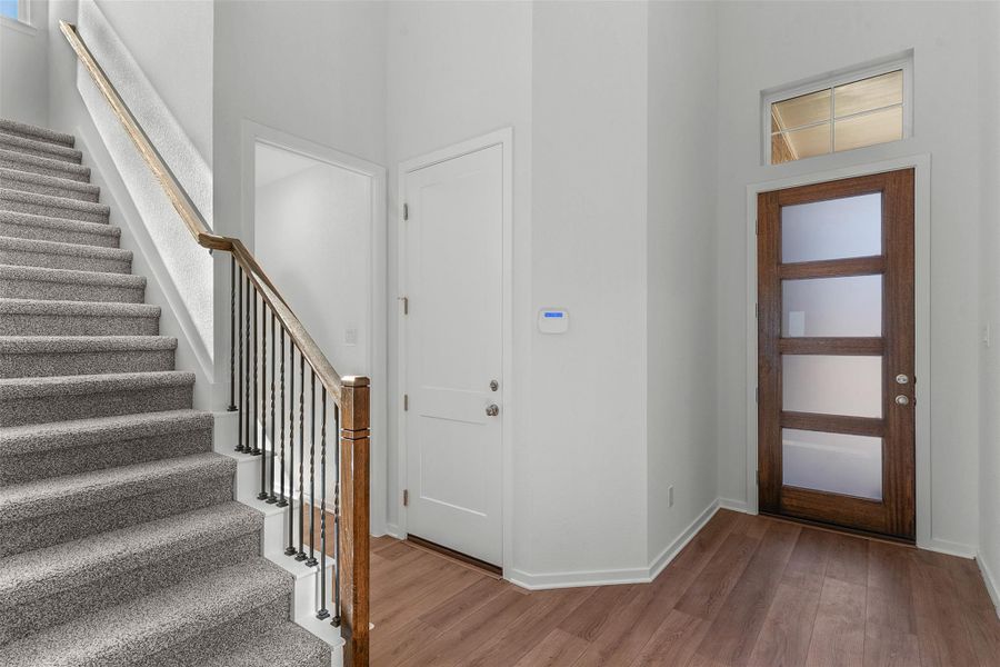 Foyer entrance with stairs, wood finished floors, healthy amount of natural light, and a high ceiling