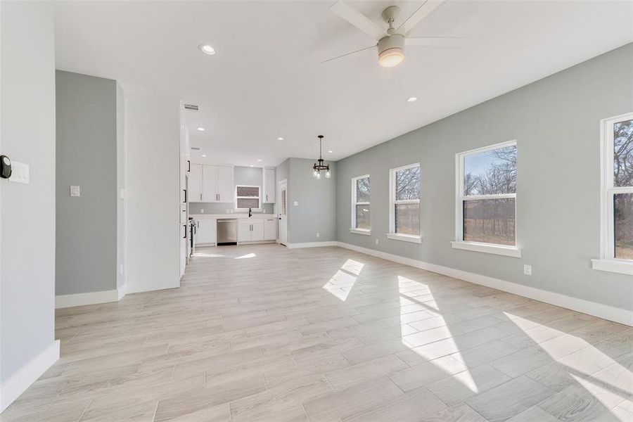 Unfurnished living room featuring ceiling fan with notable chandelier