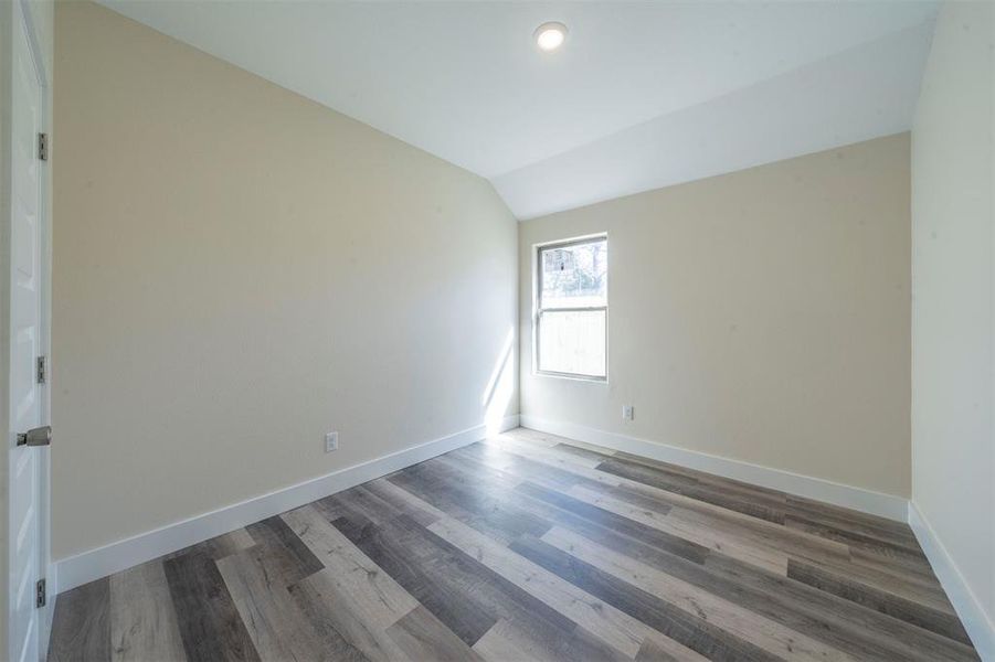 Spare room with lofted ceiling, wood finished floors, and baseboards