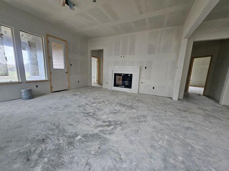 Spacious interior featuring an integrated fireplace, multiple large windows, and a rear exterior door Spacious interior featuring an integrated fireplace, multiple large windows, and a rear exterior door