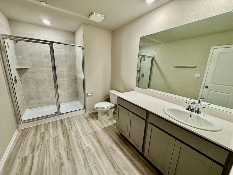 Bathroom with a stall shower, vanity, light wood finished floors, and recessed lighting