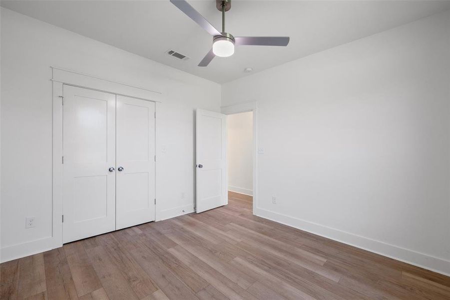 Room featuring wood-finish flooring, crisp white walls, and a contemporary ceiling fan with integrated lighting