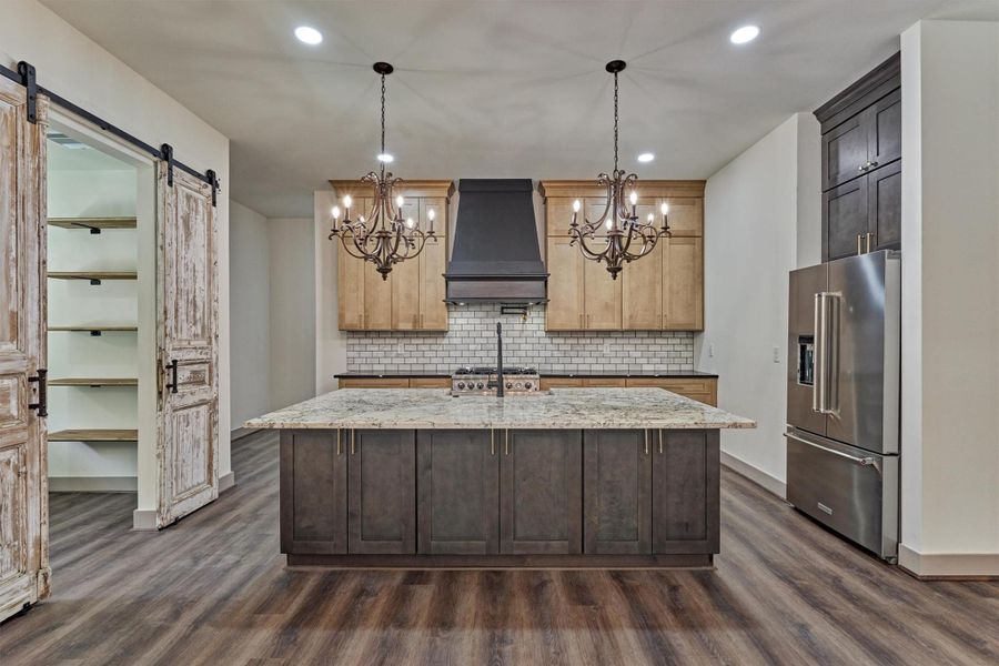 Elegant chandeliers paired with recessed lighting create a warm and inviting ambiance in the kitchen, enhancing both its beauty and functionality