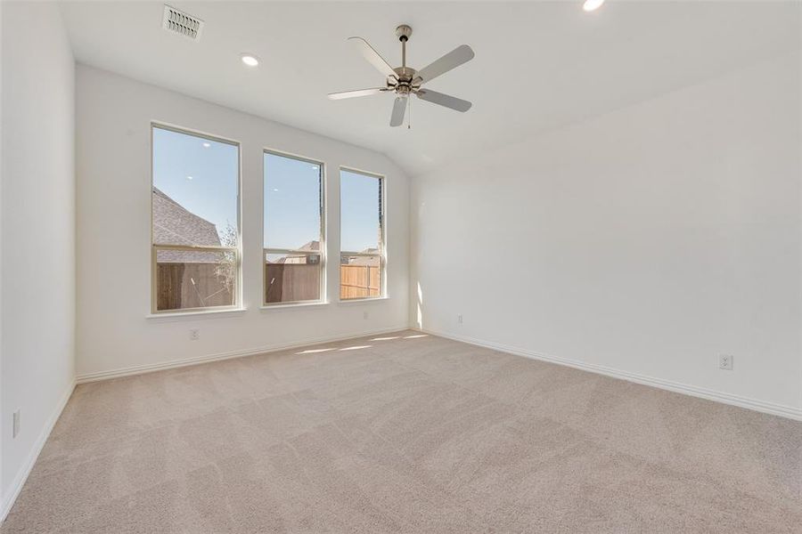 Empty room featuring light carpet, lofted ceiling, and ceiling fan