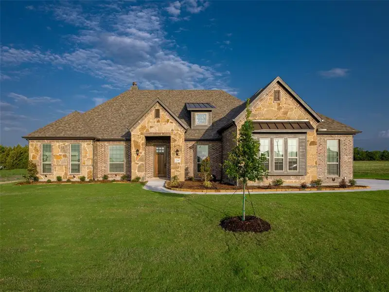 View of front facade with a front lawn, stone siding, a standing seam roof, and a shingled roof View of front facade with a front lawn, stone siding, a standing seam roof, and a shingled roof