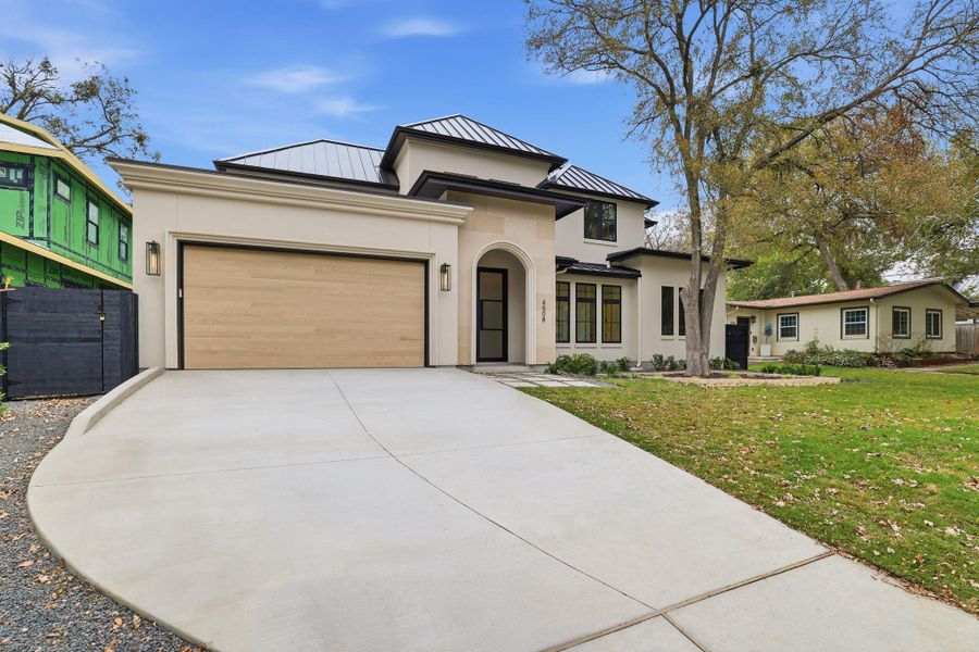 Prairie-style home with a standing seam roof, a metal roof, stucco siding, an attached garage, and a front yard