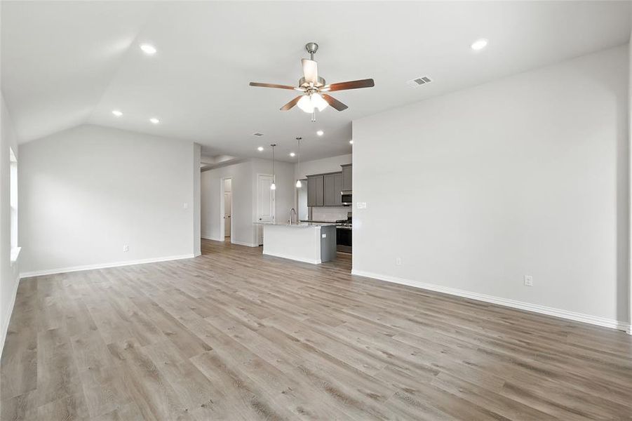 Unfurnished living room featuring recessed lighting, a ceiling fan, light wood-style floors, and lofted ceiling