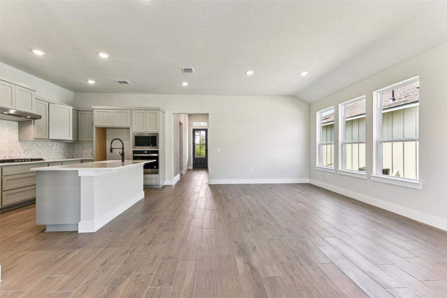 Kitchen with recessed lighting, plenty of natural light, an island with sink, gray cabinets, and decorative backsplash Kitchen with recessed lighting, plenty of natural light, an island with sink, gray cabinets, and decorative backsplash