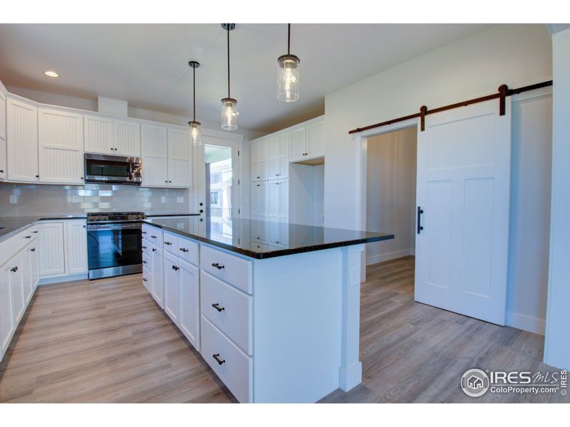 The kitchen is loaded with cabinets and has lots of counter space. The pocket office/flex room is behind the barn door to the right