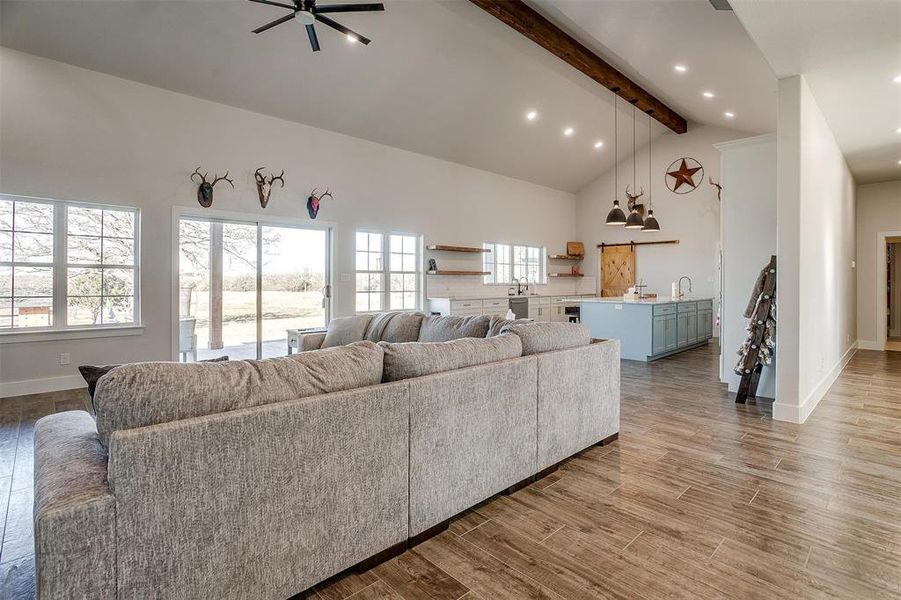 Living room with a healthy amount of sunlight, high vaulted ceiling, beamed ceiling, and wet bar