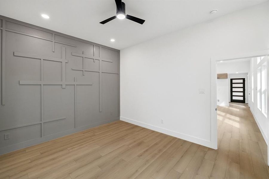 Unfurnished bedroom with light wood finished floors, a decorative wall, a ceiling fan, and recessed lighting