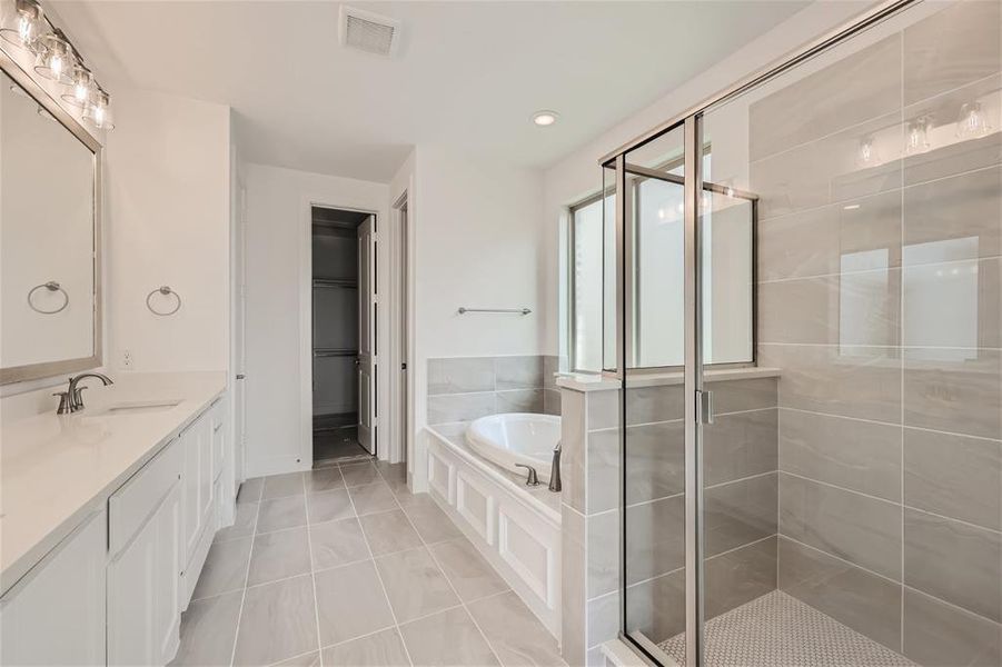 Bathroom with tile flooring, separate shower and tub, and large vanity