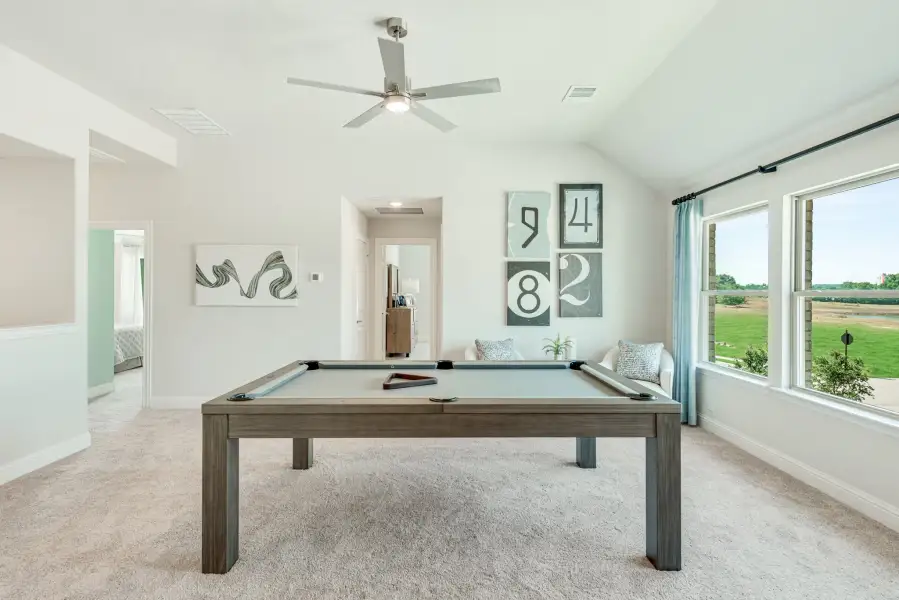 Game room with pool table, vaulted ceiling, ceiling fan, and large windows overlooking backyard