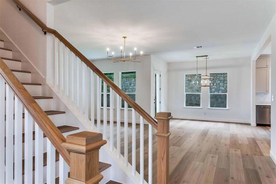 Stairway with a chandelier, wood finished floors, and plenty of natural light