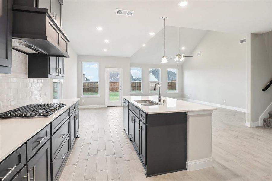 Kitchen featuring ceiling fan, sink, a kitchen island with sink, stainless steel appliances, and decorative backsplash