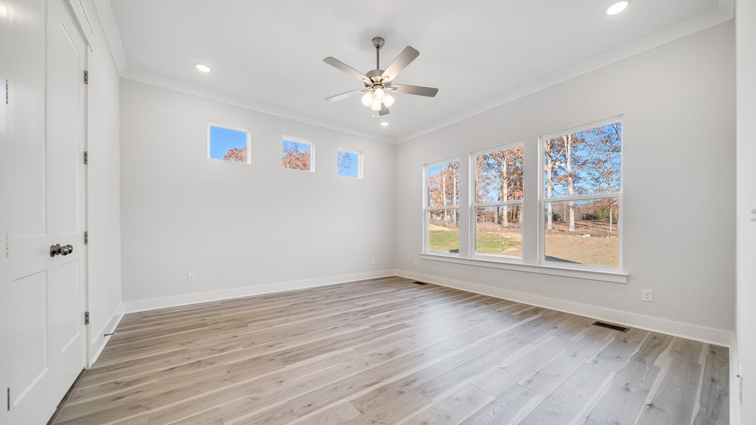 Large bedroom with hard-surface flooring, 6 windows, and ceiling fan