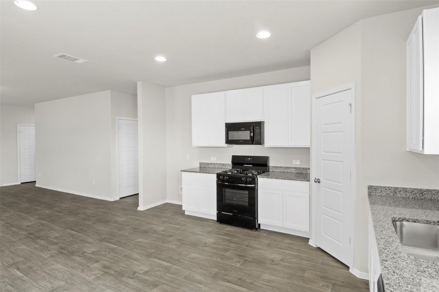 Kitchen featuring black appliances, recessed lighting, wood finished floors, and white cabinets Kitchen featuring black appliances, recessed lighting, wood finished floors, and white cabinets