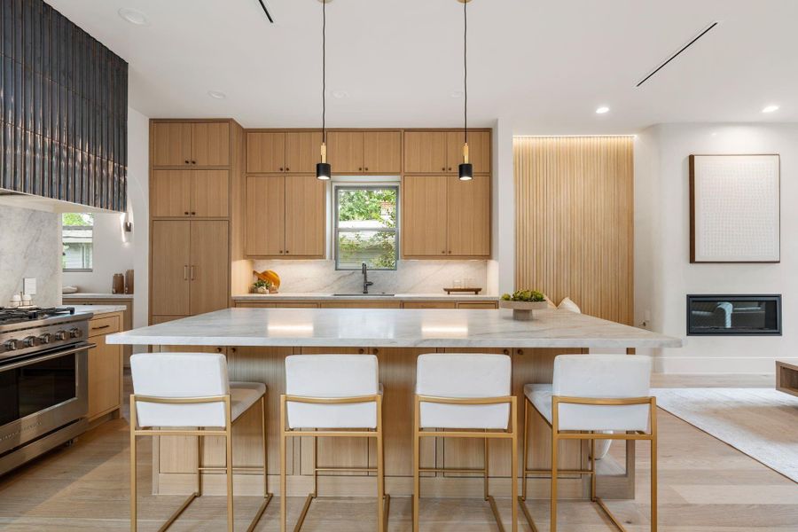 The stunning chef’s kitchen is designed for both function and style, featuring an oversized island with additional cabinetry beneath the overhang, custom white oak cabinetry, and linear slot AC registers seamlessly flush with the ceiling above. The stunning chef’s kitchen is designed for both function and style, featuring an oversized island with additional cabinetry beneath the overhang, custom white oak cabinetry, and linear slot AC registers seamlessly flush with the ceiling above.
