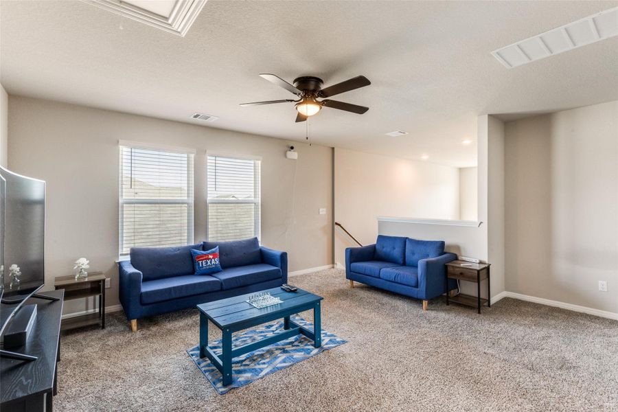 Living room featuring carpet flooring, a ceiling fan, and a textured ceiling