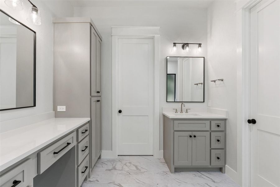 Luxurious marble-look tile floors complement the sleek, light gray vanities.