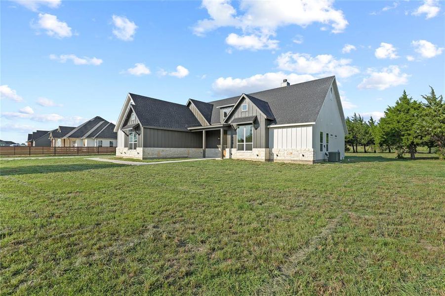 Rear view of property featuring stone siding, board and batten siding, and roof with shingles Rear view of property featuring stone siding, board and batten siding, and roof with shingles