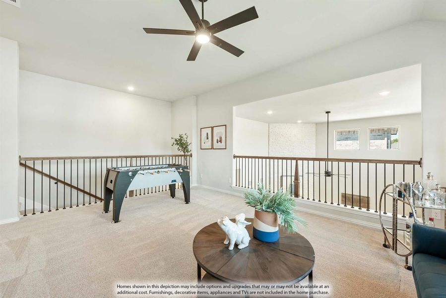 Open loft game room with foosball table, ceiling fan, carpet, and metal stair railing overlooking lower level Open loft game room with foosball table, ceiling fan, carpet, and metal stair railing overlooking lower level