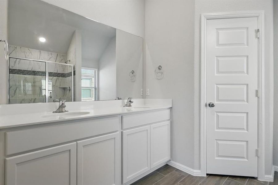 Full bathroom with double vanity, a shower stall, and wood finished floors Full bathroom with double vanity, a shower stall, and wood finished floors