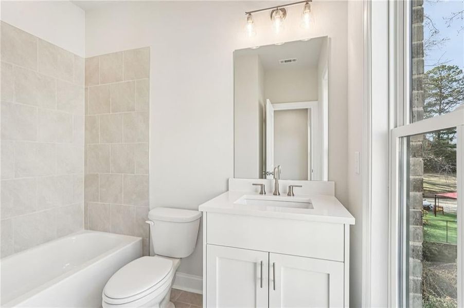 Bedroom 2 ensuite bathroom featuring upgraded vanity cabinet and quartz top with accented light fixture over mirror
