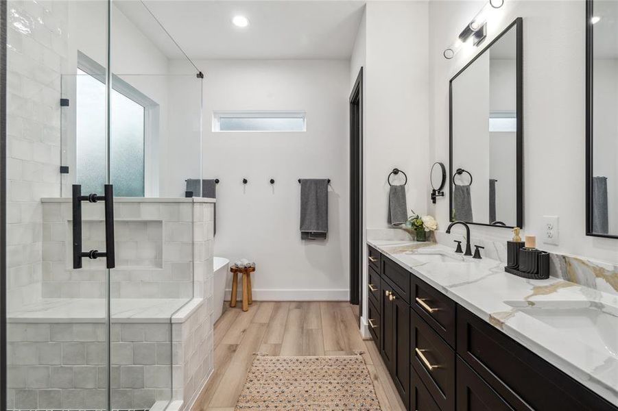 The walk-in shower, with its stylish tilework, and the double vanity with quartz countertops, create a serene, modern atmosphere perfect for unwinding after a long day.