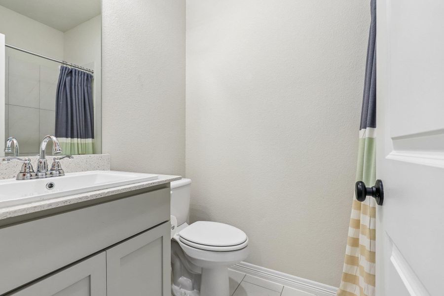 A well-appointed bathroom features a single vanity with a sleek countertop and an adjacent commode.