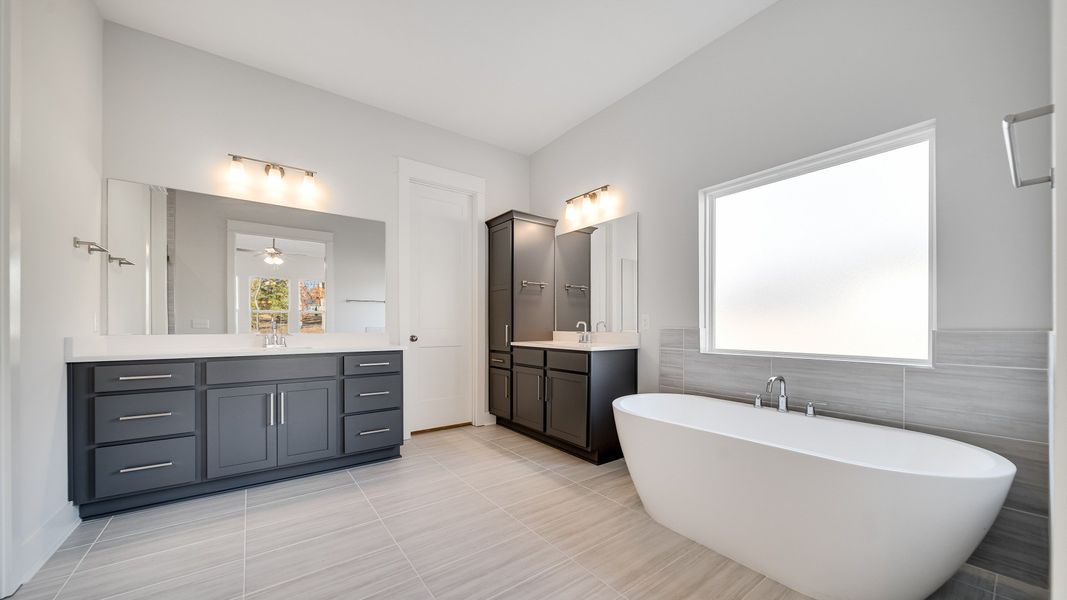 Large bathroom with tiled and glass shower, freestanding tub and modern gray cabinetry and vanity