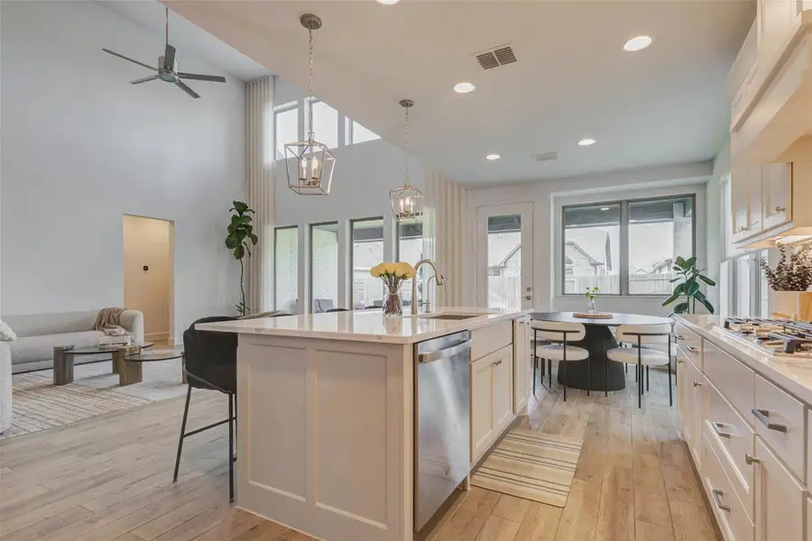 Open-concept kitchen and living area with high ceilings, large windows, and natural light. The kitchen boasts a central island, sleek cabinetry, and stainless steel appliances, while the adjacent living space offers a cozy seating area. Open-concept kitchen and living area with high ceilings, large windows, and natural light. The kitchen boasts a central island, sleek cabinetry, and stainless steel appliances, while the adjacent living space offers a cozy seating area.