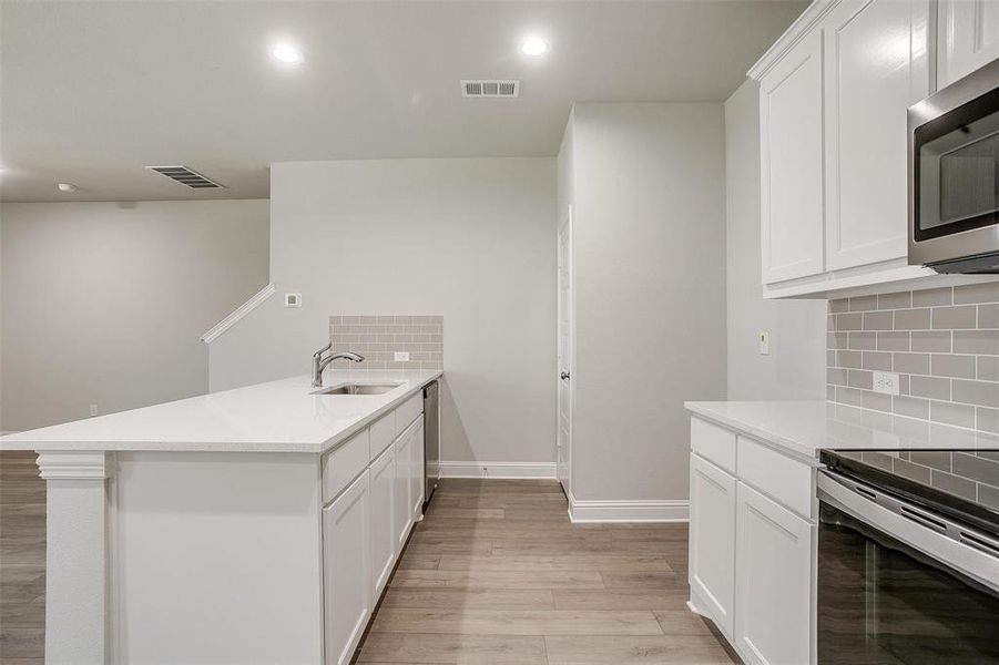 Kitchen featuring white cabinets, light stone countertops, stainless steel appliances, a peninsula, and recessed lighting