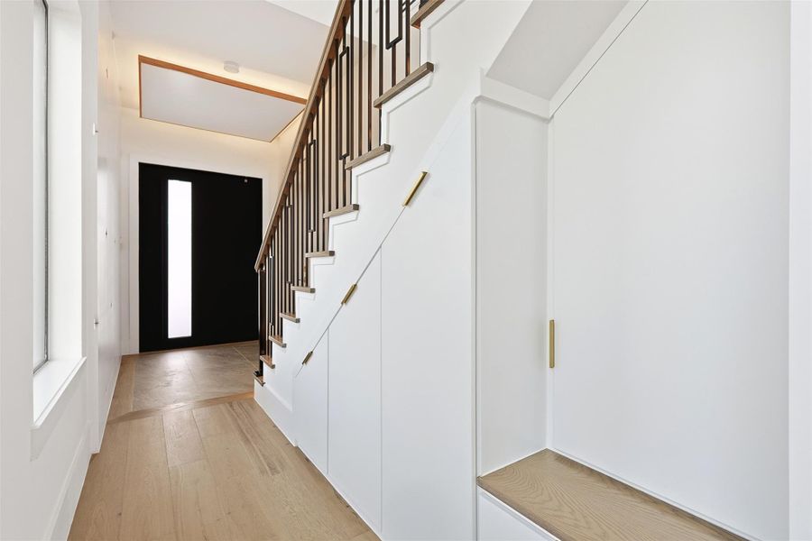 Same floorplan - different finishes. The hallway maximizes utility with custom built-in under-stair storage and a dedicated mudroom bench with gold hardware.