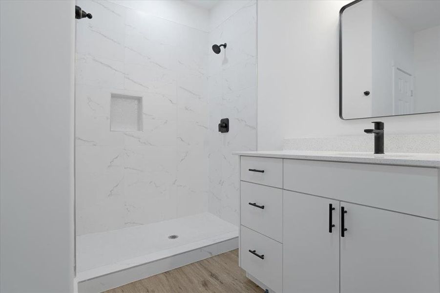 Bathroom with tiled shower, vanity, and hardwood / wood-style flooring