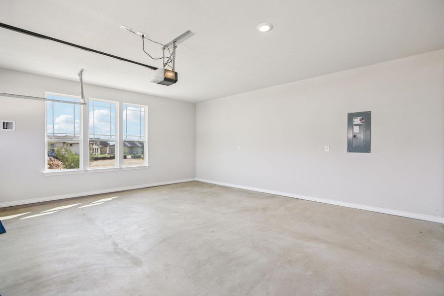 Garage with electric panel, recessed lighting, and a garage door opener