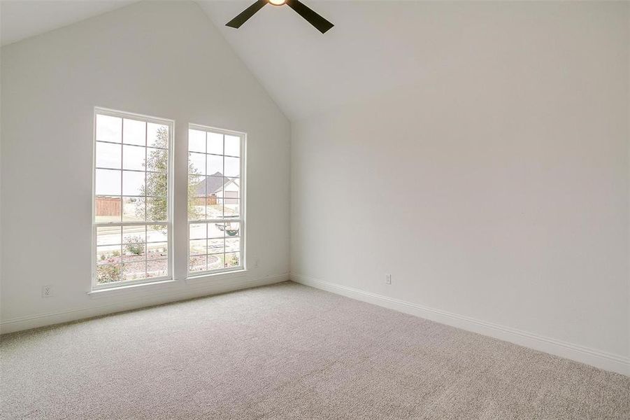 Carpeted empty room featuring high vaulted ceiling and ceiling fan