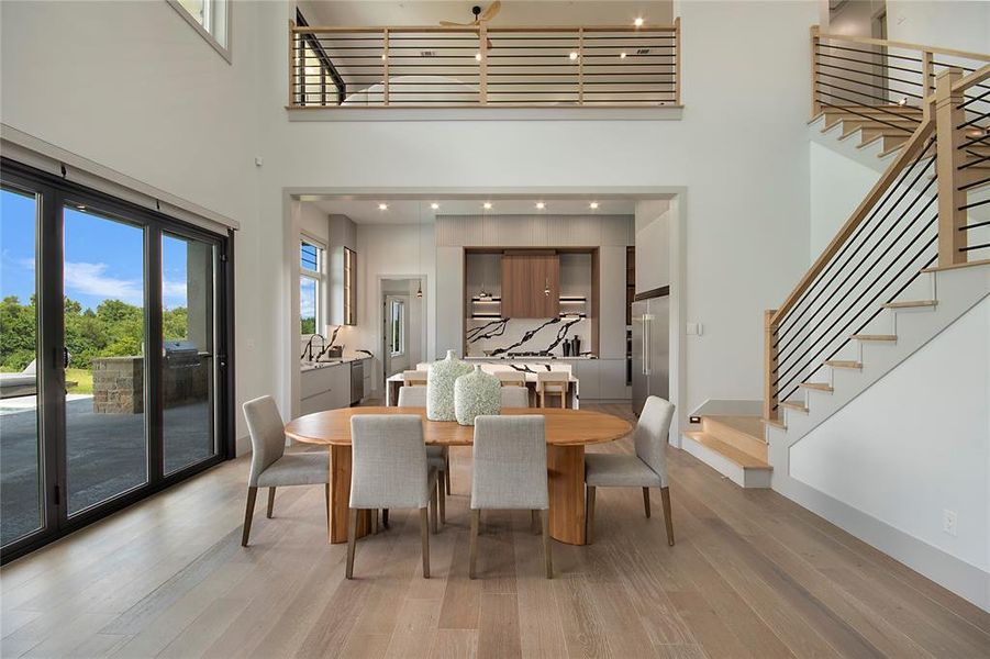 Dining room with a towering ceiling, stairs, and light wood-type flooring
