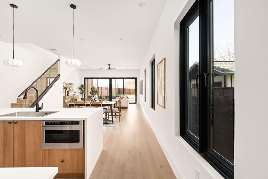 Kitchen with open floor plan, light stone counters, hanging light fixtures, light wood-style flooring, and modern cabinets