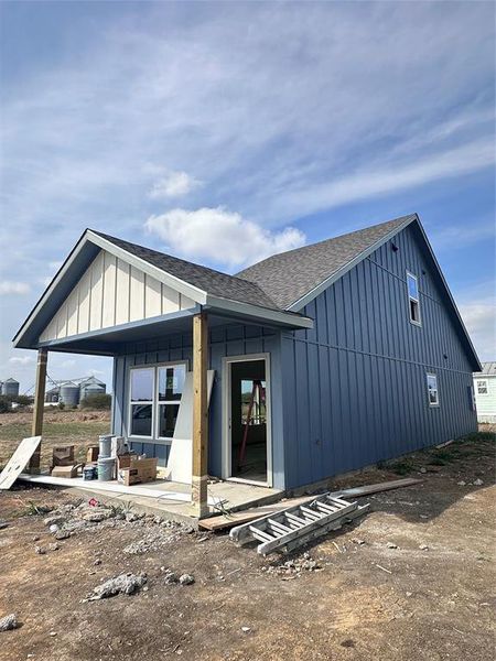 Rear view of property with roof with shingles, board and batten siding, and covered porch Rear view of property with roof with shingles, board and batten siding, and covered porch