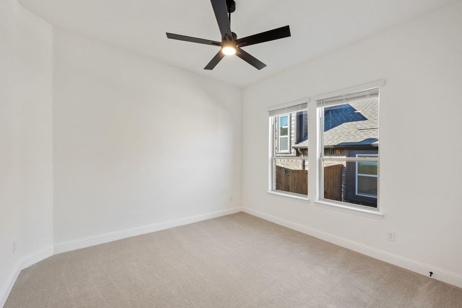 Empty bedroom with beige carpet, white walls, black ceiling fan, and double windows Empty bedroom with beige carpet, white walls, black ceiling fan, and double windows