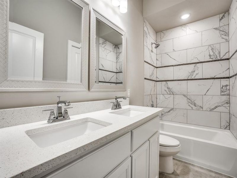 Bathroom featuring a sink, toilet, double vanity, and shower / bathtub combination