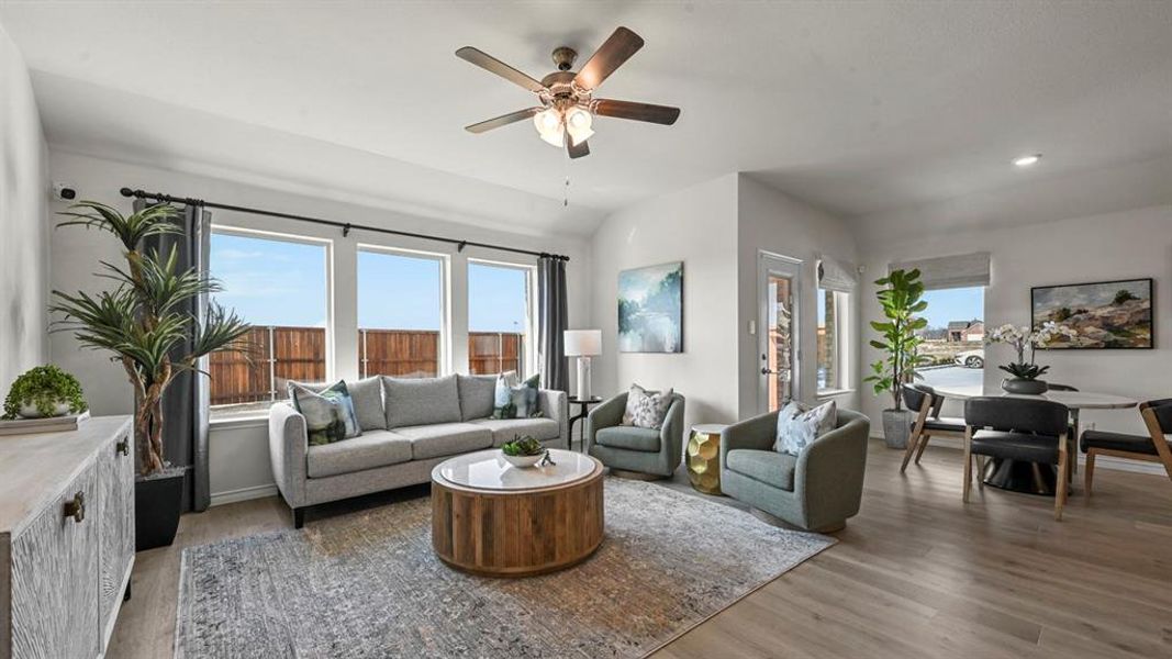 Living room with light wood-style flooring, ceiling fan, and lofted ceiling